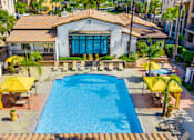 Thumbnail 70 of 80 - A pool surrounded by yellow sun shades and a white building with a blue door.