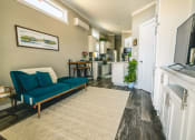 Thumbnail 18 of 97 - a living room with a couch and a kitchen in the background
