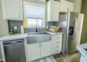 Thumbnail 21 of 97 - New Apartments In South Austin - Casata Austin - Kitchen With Marbled Countertops, White Cabinets, Modern Stainless-Steel Appliances, And A Window.