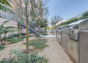 Thumbnail 9 of 26 - A small garden with a tree and a metal structure at Wilshire Valencia Apartment, Los Angeles, 90017