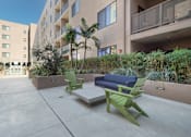 Thumbnail 25 of 26 - A patio with a couch, chairs and a table with a planter in between at Wilshire Valencia Apartment, Los Angeles