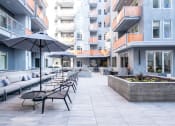 Thumbnail 14 of 18 - a patio with tables and umbrellas in front of an apartment building