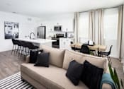 Thumbnail 12 of 50 - a living area with a couch table and chairs and a kitchen in the background
