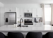 Thumbnail 11 of 50 - a kitchen with white cabinets and a large white island with black chairs