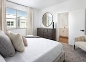 Thumbnail 14 of 50 - a bedroom with a large bed and a dresser with a mirror