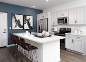 Thumbnail 3 of 50 - a kitchen with white cabinetry and a large white island with a white countertop and black