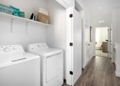 Thumbnail 22 of 50 - a white washer and dryer in a white laundry room with a wooden floor