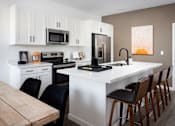 Thumbnail 28 of 50 - a kitchen with white cabinets and a large white island with black chairs