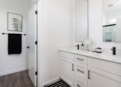 Thumbnail 32 of 50 - a bathroom with white cabinets and a black rug