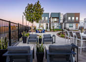 Thumbnail 45 of 50 - a rendering of a patio with chairs and tables in front of apartments