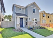Thumbnail 104 of 149 - A grey house with a blue door and a small front yard.