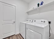 Thumbnail 107 of 149 - A white door is on the left of a white washing machine and dryer.