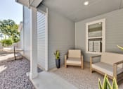 Thumbnail 105 of 149 - A patio with a couch, chair, and potted plant.