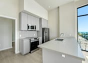 Thumbnail 55 of 117 - A kitchen with a white counter top and stainless steel appliances at Skyview Sunset Apartments, California