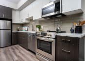 Thumbnail 35 of 89 - Apartments In DTLA For Rent - Kitchen With Stainless-Steel Appliances, White Cabinets, And Wood-Style Floors