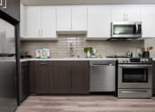 Thumbnail 36 of 89 - Apartments In DTLA For Rent - Kitchen With Stainless-Steel Appliances, White Cabinets, And Wood-Style Floors