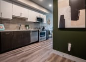 Thumbnail 37 of 89 - Apartments For Rent In South Park, Los Angeles CA - Emerald - A Stylish And Modern Kitchen With Stainless Steel Appliances, White Countertops, White Cabinetry Above, And Dark Wood Cabinetry Below