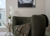 Thumbnail 39 of 89 - a living room with a green chair and a white orchid in a white vase