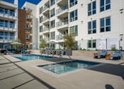 Thumbnail 48 of 89 - a pool and hot tub overlooked by an apartment building