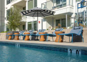 Thumbnail 49 of 89 - a poolside deck with lounge chairs and an umbrella