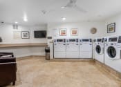 Thumbnail 32 of 36 - the laundry room is equipped with washes and dryers and a television at 55+ FountainGlen Goldenwest Senior Apartments, Westminster