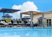 Thumbnail 8 of 34 - a swimming pool with chairs and umbrellas at 55+ FountainGlen Valencia, Valencia, California