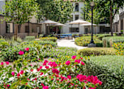Thumbnail 29 of 34 - A garden with pink flowers in the foreground and a building in the background. at 55+ FountainGlen Terra Vista, Rancho Cucamonga, CA, 91730