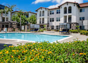 Thumbnail 12 of 34 - A pool surrounded by flowers and a building in the background. at 55+ FountainGlen Terra Vista, California, 91730