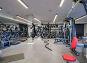 Thumbnail 9 of 21 - A gym with a variety of equipment including treadmills, weights, and exercise machines.