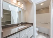 Thumbnail 34 of 45 - A bathroom with a sink, mirror, and toilet.