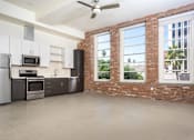 Thumbnail 12 of 68 - apartment unit kitchen with stainless steel appliances and a brick wall with large windows. at Imperial Hardware Lofts, California