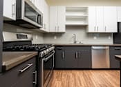 Thumbnail 14 of 68 - a kitchen with stainless steel appliances and white cabinets and dark bottom cabinets at Imperial Hardware Lofts, Riverside