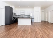Thumbnail 8 of 68 - an empty living room with a kitchen and white cabinets at Imperial Hardware Lofts, Riverside, CA