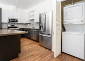 Thumbnail 10 of 68 - White stackable washer and dryer, kitchen with stainless appliances at Imperial Hardware Lofts, Riverside