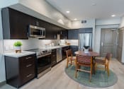 Thumbnail 10 of 83 - Eat-In Kitchen With Dining Room Table, Black Cabinets, White Countertops, And Stainless-Steel Appliances. at Bayswater Apartments, Burlingame, 94010