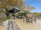 Thumbnail 12 of 40 - A patio with a gazebo, chairs, and an umbrella.