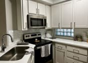 Thumbnail 18 of 18 - Kitchen with white cabinets and black oven range with microwave above it.