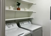Thumbnail 15 of 18 - a white washer and dryer in a laundry room with shelves