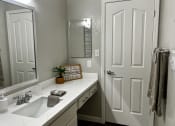 Thumbnail 11 of 18 - a bathroom with a sink and a mirror and a door