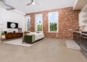 Thumbnail 39 of 68 - a living room with a couch and a brick wall and a kitchen with a stove at Imperial Hardware Lofts, California, 92501