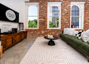 Thumbnail 44 of 68 - a living room with a green couch and a brick wall at Imperial Hardware Lofts, Riverside