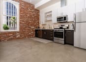 Thumbnail 45 of 68 - a kitchen with a brick wall and stainless steel appliances at Imperial Hardware Lofts, Riverside, 92501