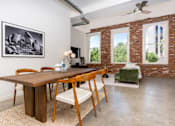 Thumbnail 50 of 68 - a dining room with a wooden table and chairs and a living room with exposed brick at Imperial Hardware Lofts, California