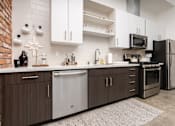 Thumbnail 52 of 68 - a kitchen with stainless steel appliances and white cabinets at Imperial Hardware Lofts, California, 92501