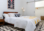Thumbnail 54 of 68 - a bedroom with a bed with white sheets and a yellow and black blanket at Imperial Hardware Lofts, California