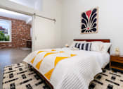 Thumbnail 55 of 68 - a bedroom with a bed and a red brick wall at Imperial Hardware Lofts, Riverside, CA