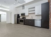 Thumbnail 17 of 68 - Kitchen with stainless appliances, white upper cabinets and dark lower cabinets at Imperial Hardware Lofts, Riverside, CA, 92501