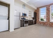 Thumbnail 15 of 68 - kitchen and laundry area with brick wall and large windows at Imperial Hardware Lofts, California
