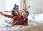Thumbnail 16 of 80 - a man and woman laying on a bed with their daughter