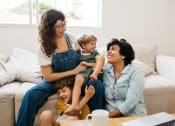 Thumbnail 15 of 60 - a mother and father sit on a couch with their children